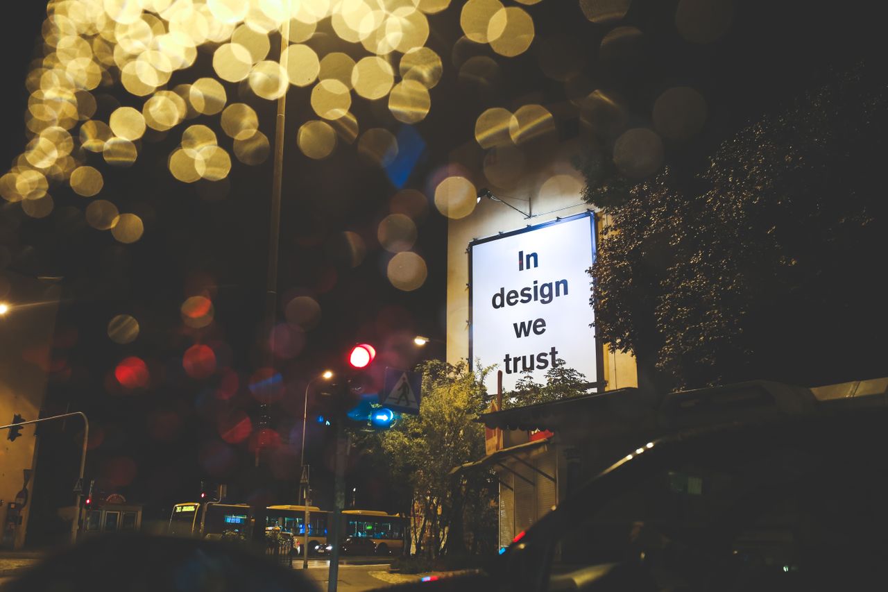 Crafting Captivating Headlines: Your awesome post title goes here A city street at night featuring an illuminated billboard with the phrase 'In design we trust.'