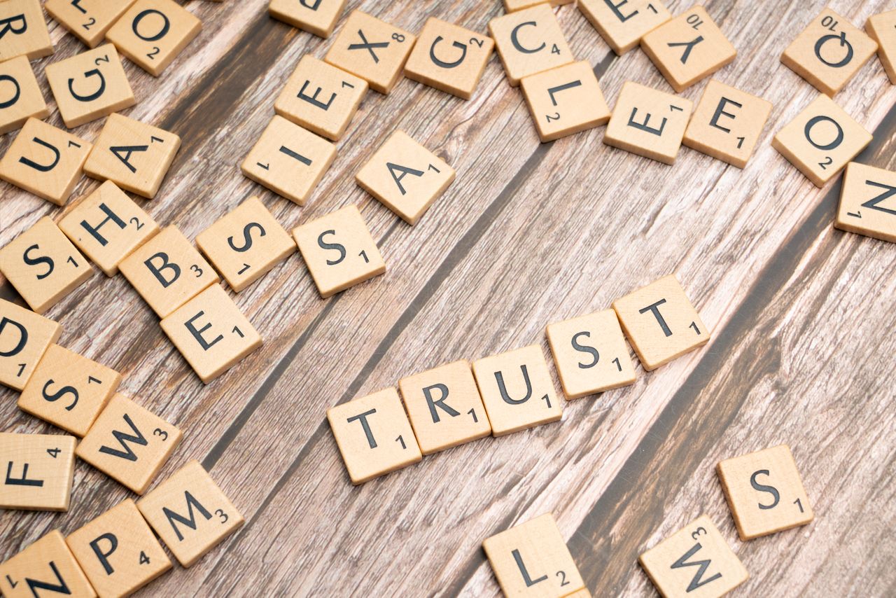 The Art of Drawing Readers In: Your attractive post title goes here Scrabble letter tiles form the word 'Trust' on a wooden table, surrounded by scattered tiles.
